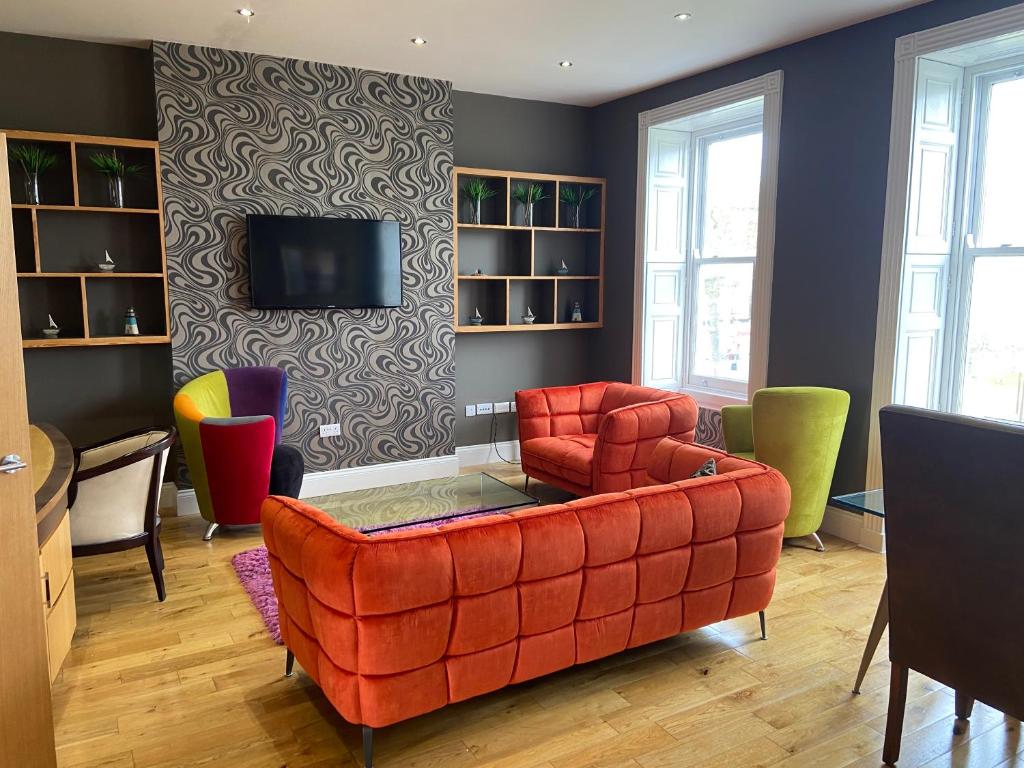 sala de estar con sofá rojo y sillas en Halvard Apartments at Castletown, en Castletown
