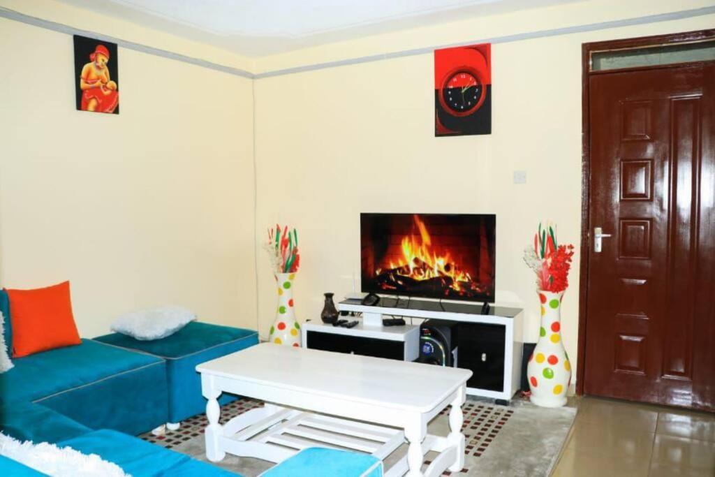 a living room with a blue couch and a fireplace at EuphGlory accomodations 1 and 2 bedrooms in Kakamega