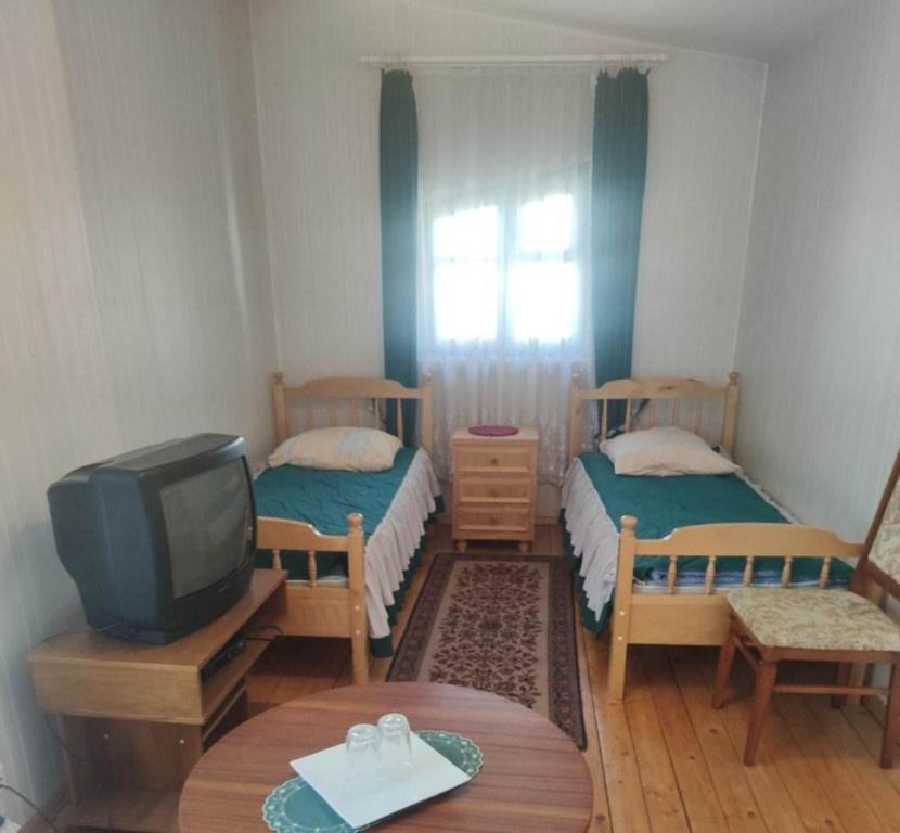 a small room with two beds and a tv at Tilžė in Šiauliai