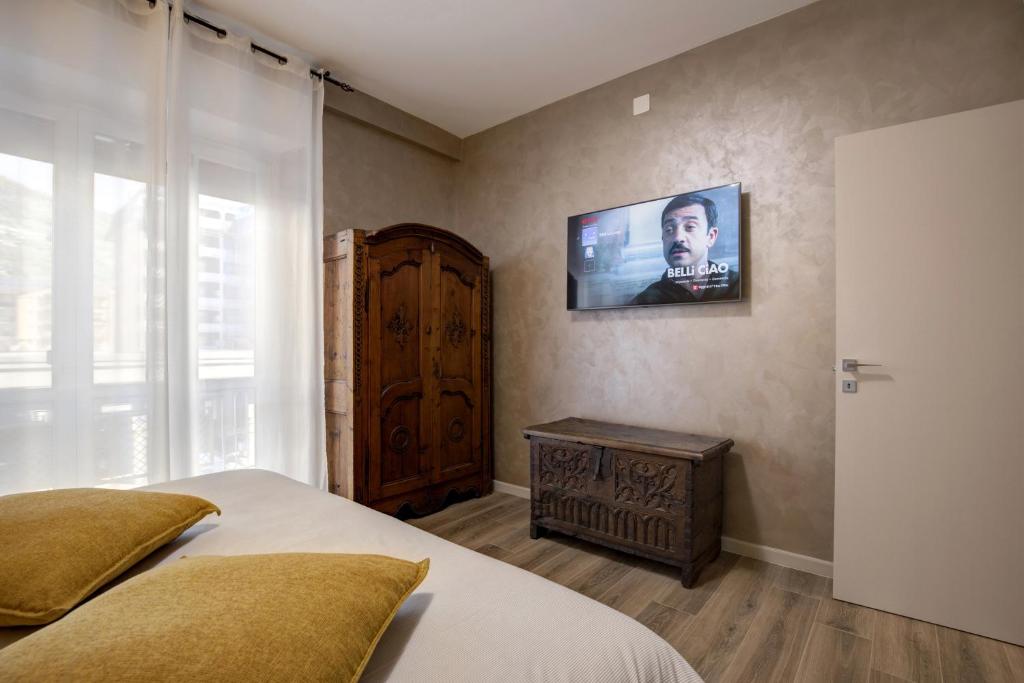 LA LUPA Appartment- In the heart of Aosta with car Box - CIR Aosta 0009 في أَويستا: غرفة نوم مع سرير وتلفزيون على الحائط