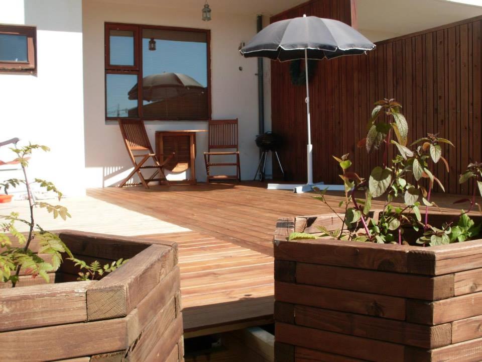 une terrasse en bois avec un parasol et quelques plantes dans l'établissement Reykjavik Apartment Garden and Terrace, à Reykjavik