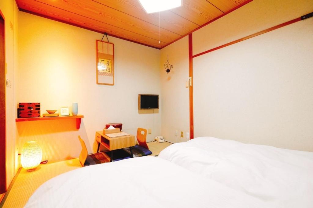1 Schlafzimmer mit einem weißen Bett und einem TV in der Unterkunft Nara Ryokan - Vacation STAY 49528v in Nara