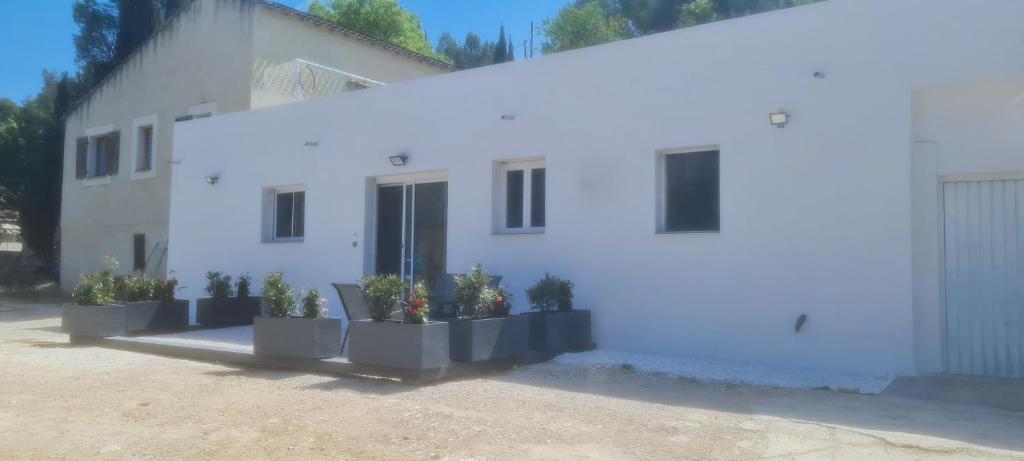 a white house with potted plants in front of it at Bas de villa au calme in Marseille