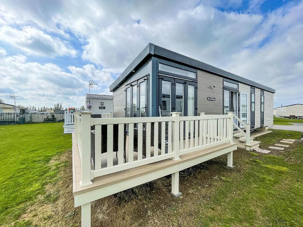 a tiny house with a porch and a fence at Modern 6 Berth Caravan At Martello Beach In Essex Ref 29002sv in Clacton-on-Sea
