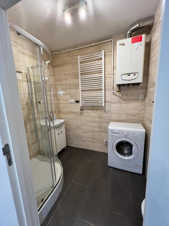 a small bathroom with a washing machine and a shower at Modern Apartment in Września