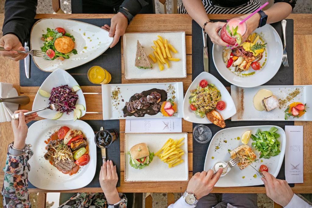 a group of people sitting around a table with plates of food at Liberty Hotels Lara in Lara