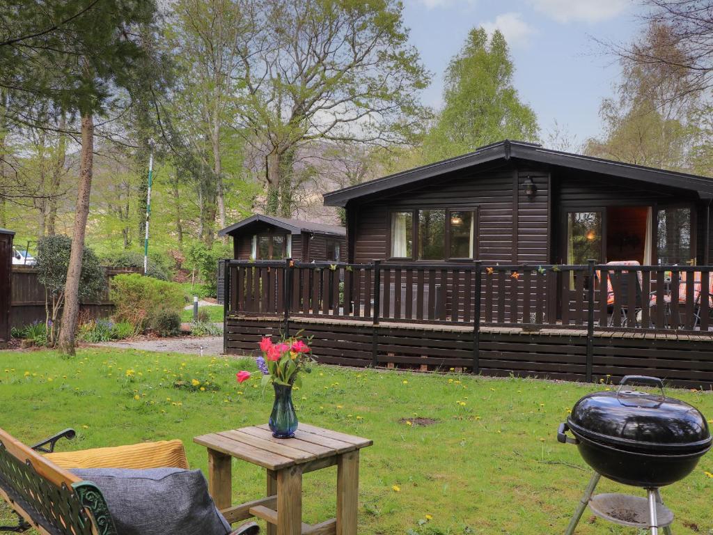 a house with a grill and a vase of flowers on a table at Derwent Lodge in Keswick