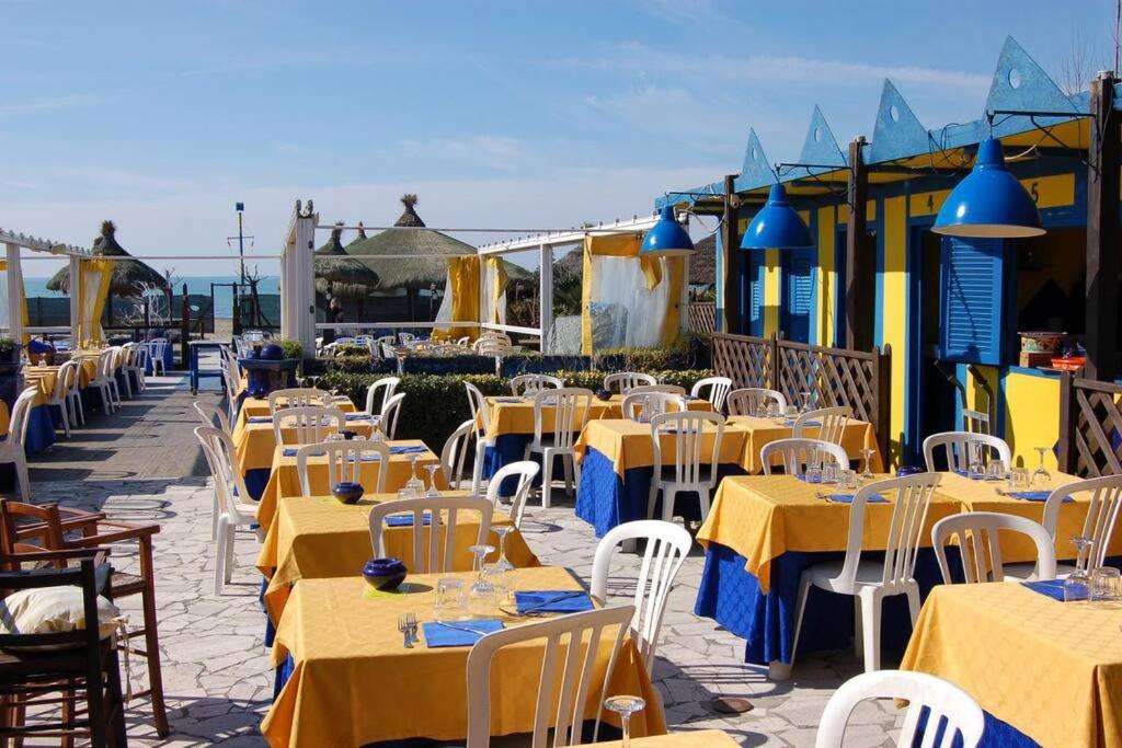 a row of tables and chairs with yellow tables and white chairs at Casa Levante Fregene, mare e relax vicino Roma in Fregene
