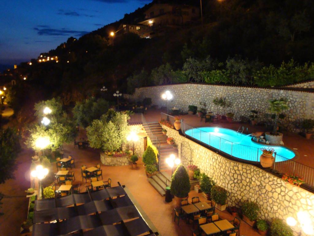 an outdoor swimming pool with tables and chairs at night at Belsito in Serrone