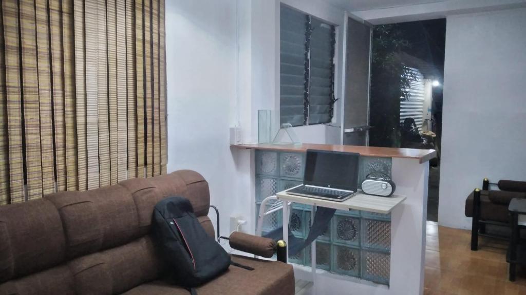 un soggiorno con divano e scrivania con computer di Mabs Hostel a El Nido
