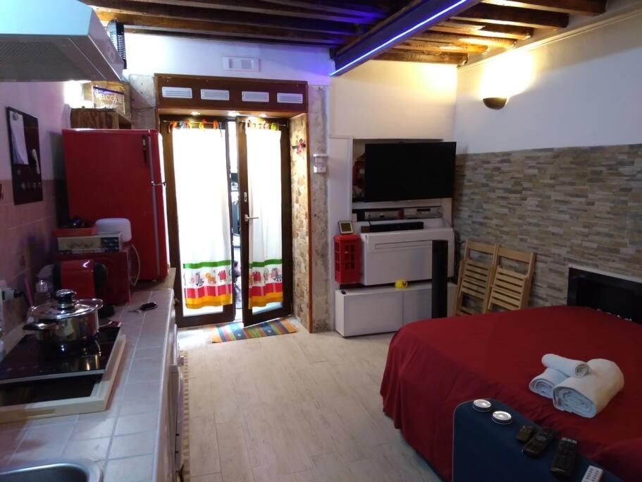 a kitchen and a living room with a red bed and a refrigerator at The little house of Ely in Siracusa