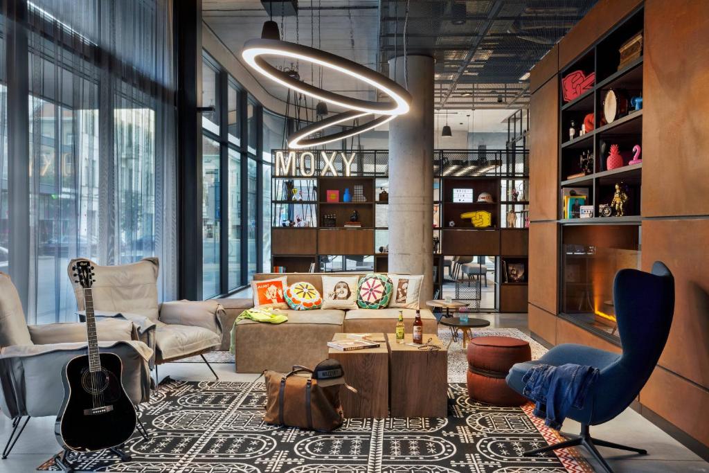 a living room filled with furniture and a guitar at Moxy Kaunas Center in Kaunas