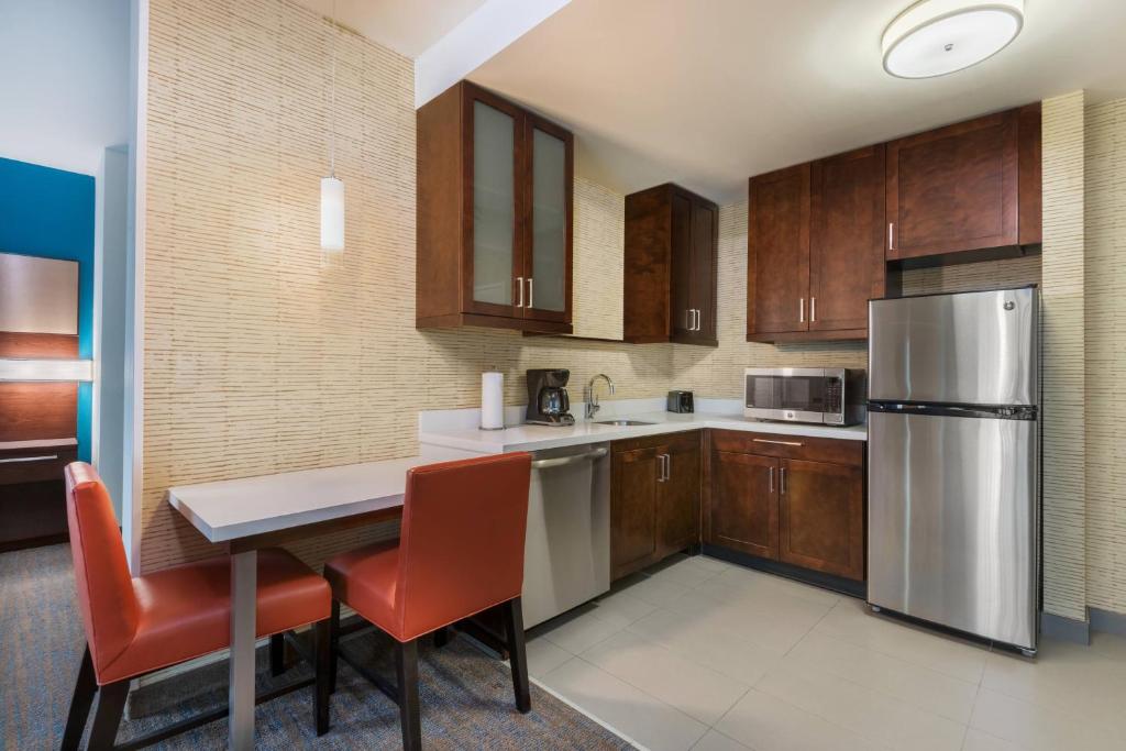 a kitchen with a table and a stainless steel refrigerator at Residence Inn by Marriott Charlotte City Center in Charlotte