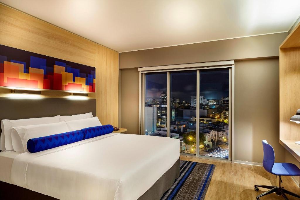 a bedroom with a large bed and a large window at Aloft Lima Miraflores in Lima