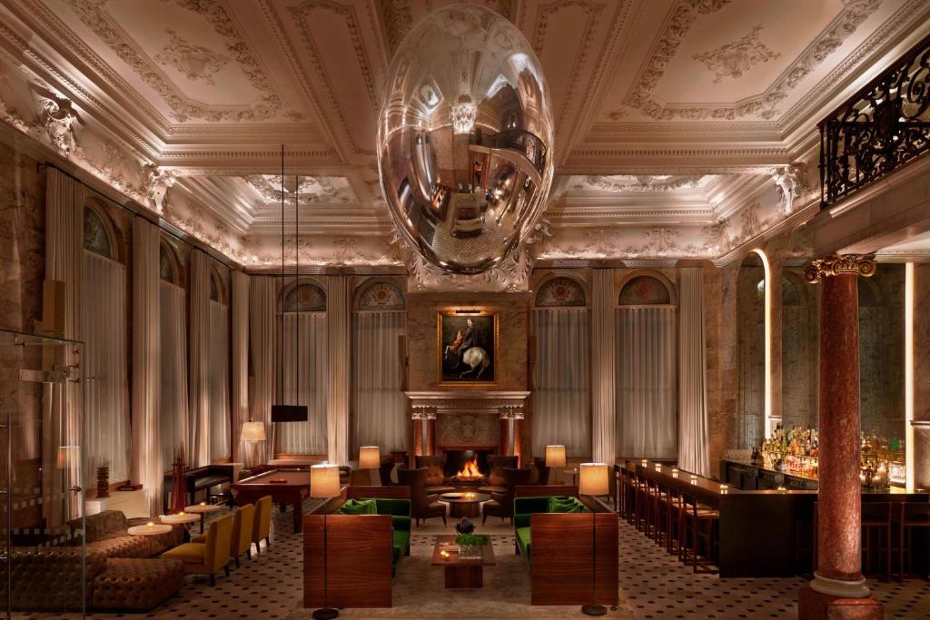 um átrio com uma grande sala com sofás e um lustre em The London EDITION em Londres