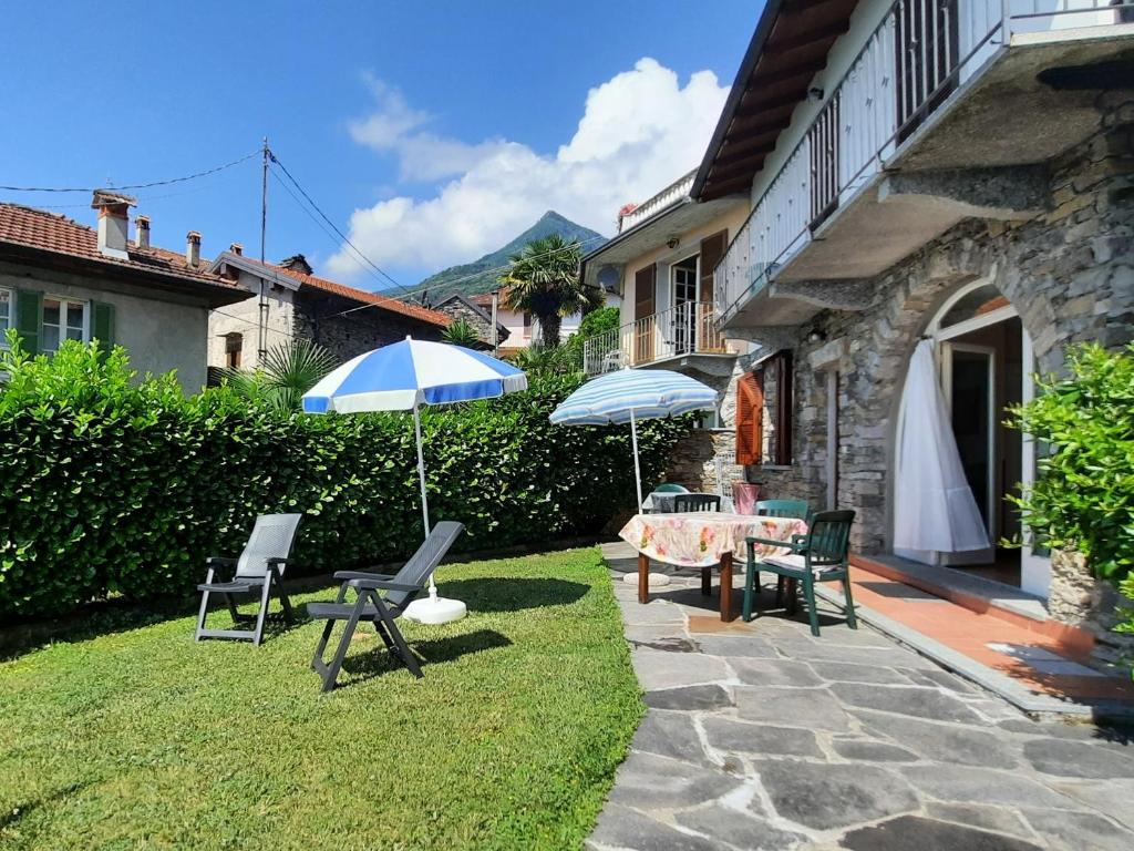 eine Terrasse mit einem Tisch, Stühlen und einem Sonnenschirm in der Unterkunft Appartamento Porto 1 in Cannero Riviera