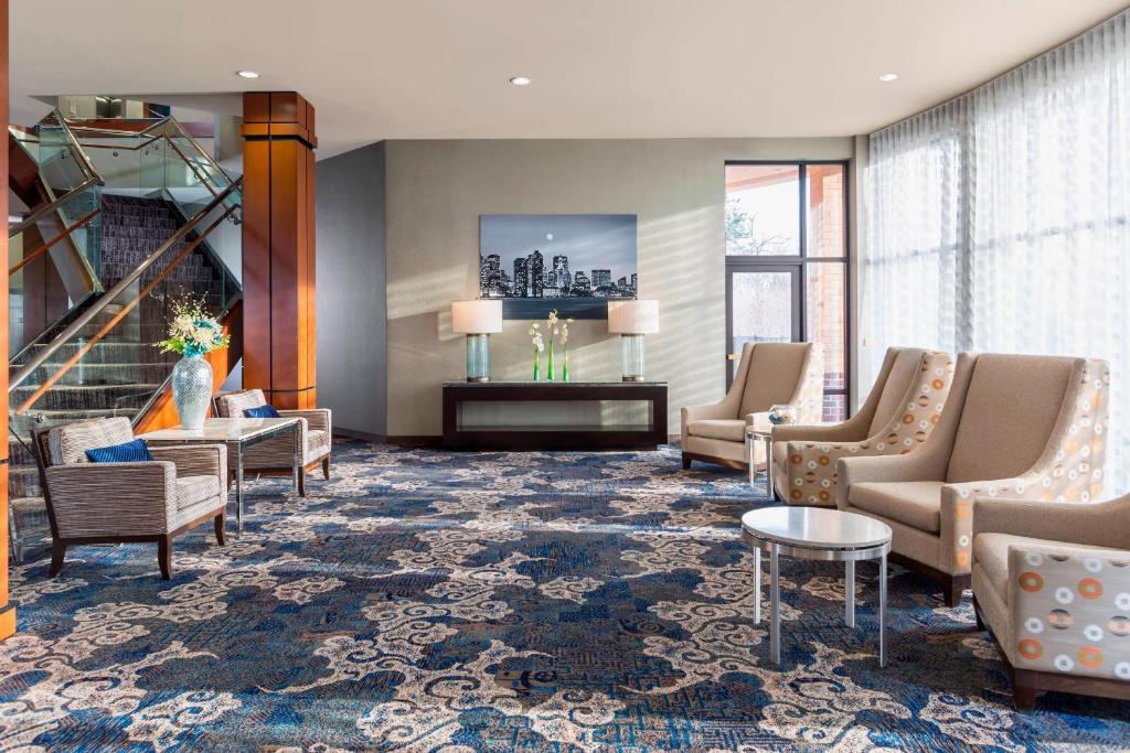 a lobby with chairs and tables and a staircase at Courtyard Boston Woburn/Boston North in Woburn