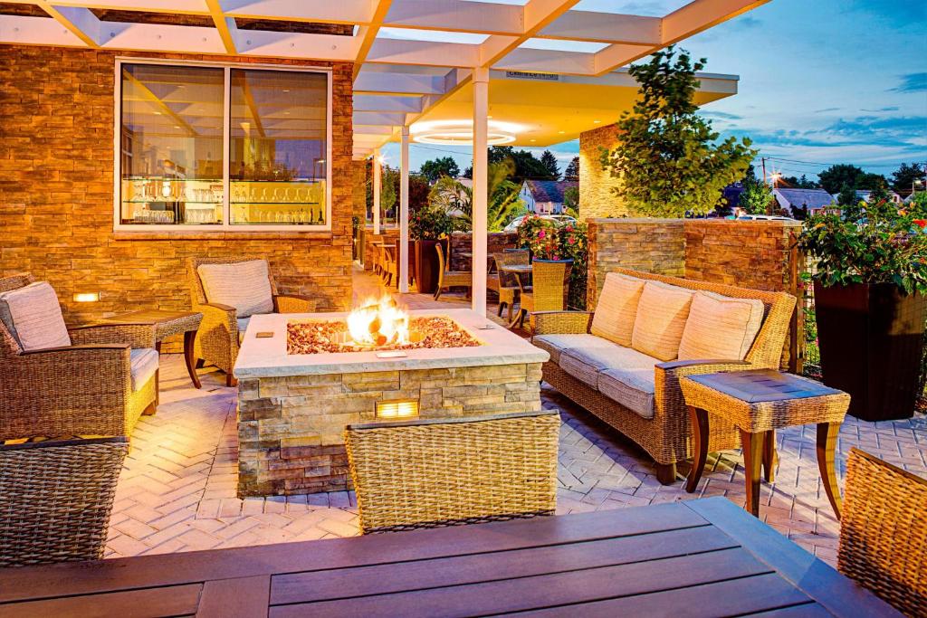 a patio with a fire pit with a table and chairs at SpringHill Suites by Marriott Carle Place Garden City in Carle Place