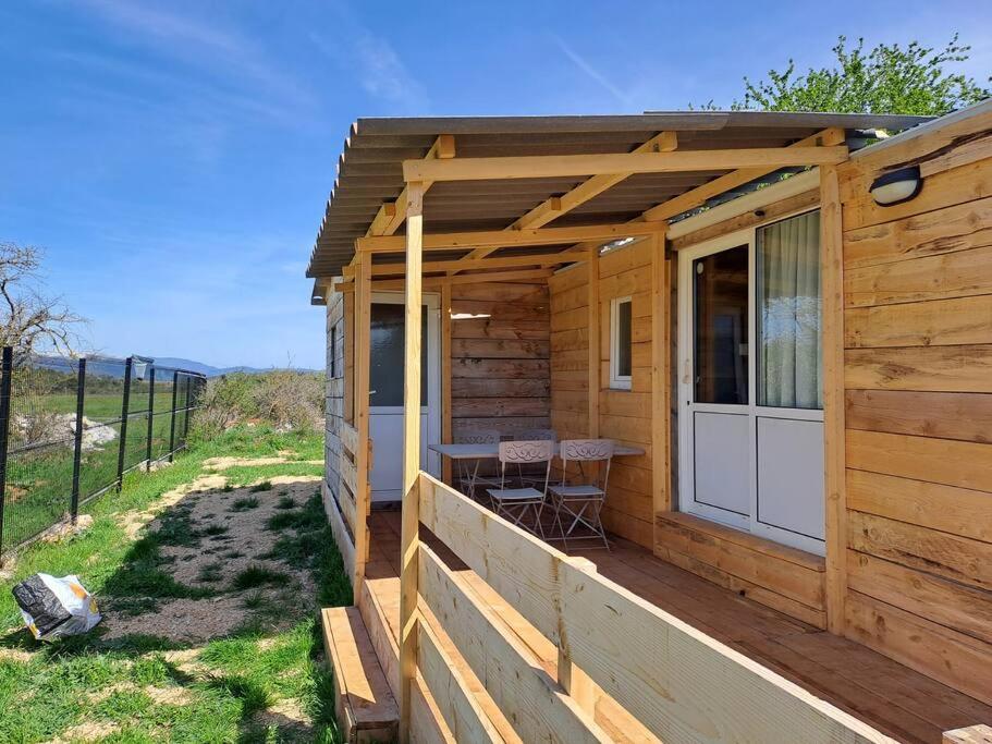 a wooden cabin with a table on a deck at A la ferme dans le Luberon 
