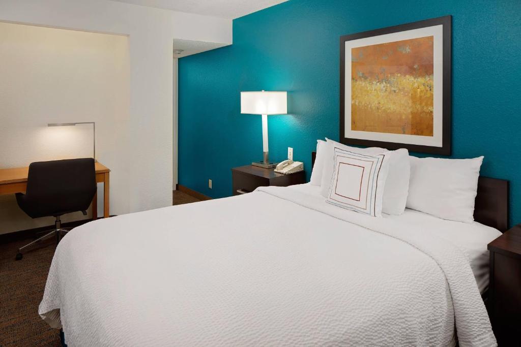 Habitación de hotel con cama blanca grande y escritorio. en Residence Inn Detroit Troy/Madison Heights, en Madison Heights