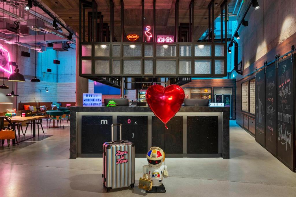 un ballon cardiaque et un jouet avec une valise dans un restaurant dans l'établissement Moxy Frankfurt City Center, à Francfort-sur-le-Main