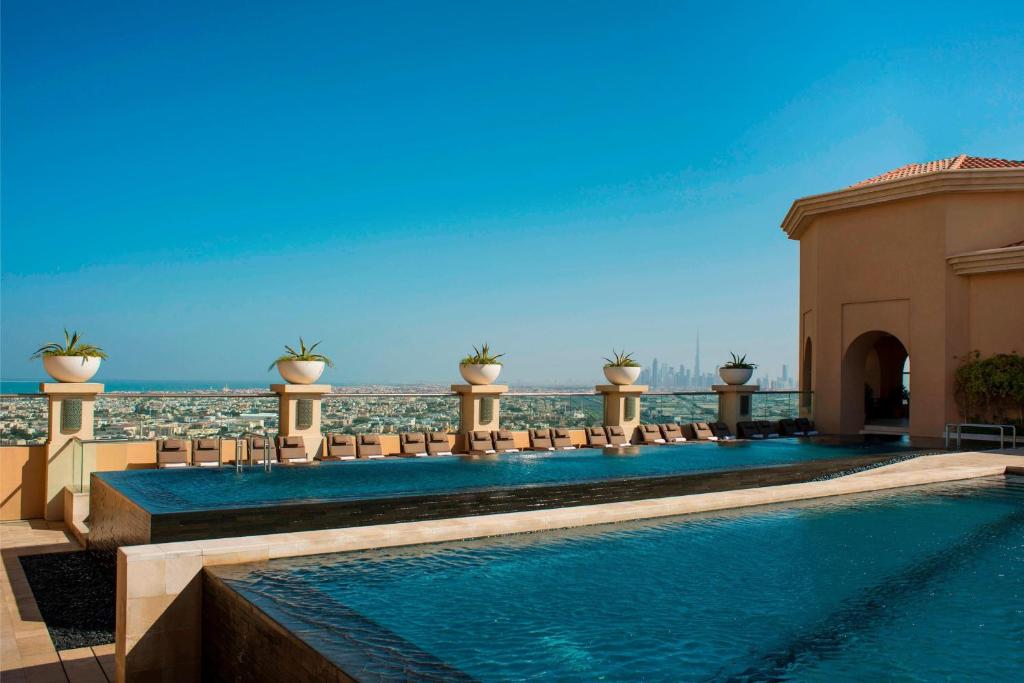 a swimming pool with chairs and the ocean in the background at Sheraton Mall of the Emirates Hotel, Dubai in Dubai