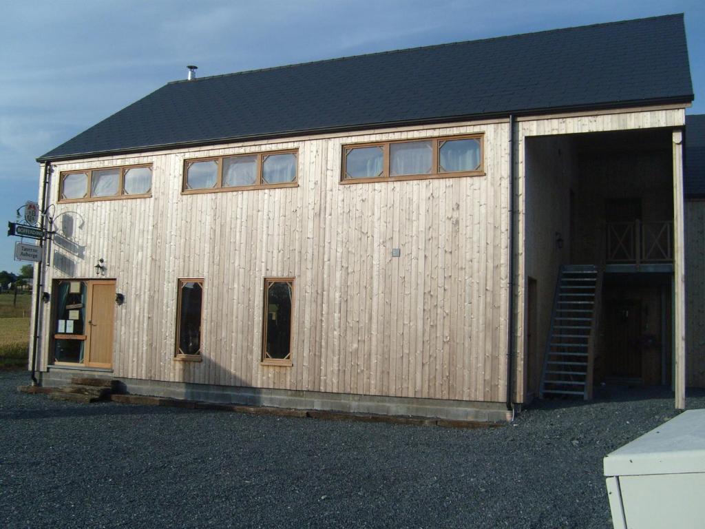 un gran edificio de madera con garaje en B&B Willow Springs Way Station, en Gouvy