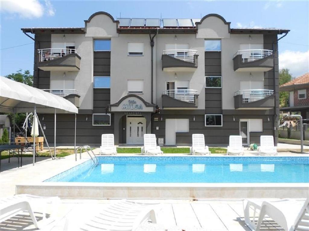 a hotel with a swimming pool and chairs and a building at Apartments Milsa Lux in Soko Banja