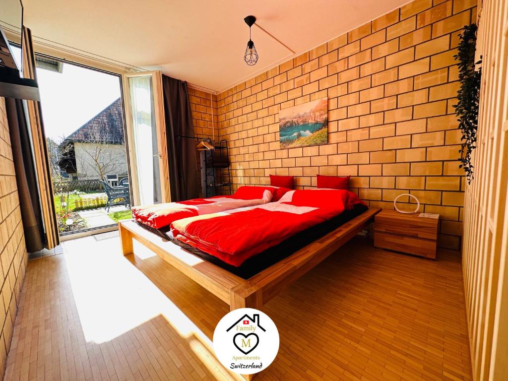 a bedroom with a red bed and a brick wall at Family M Apartments 1 in Kappel bei Olten