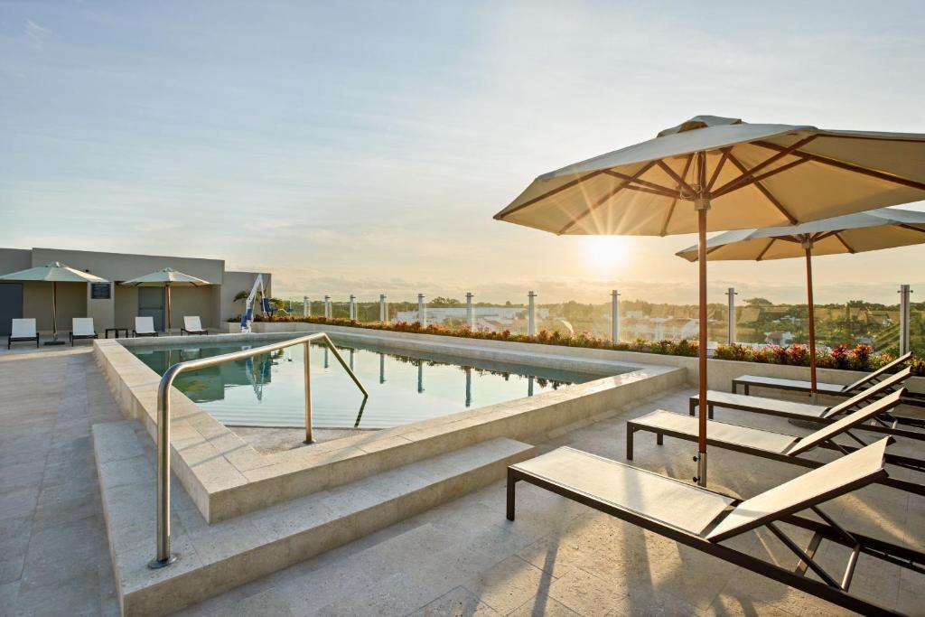 una piscina con 2 sillas y una sombrilla en Residence Inn by Marriott Playa del Carmen en Playa del Carmen