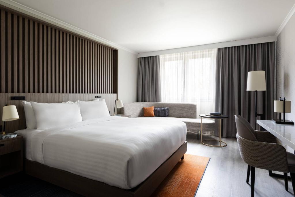 ロワシー・アン・フランスにあるパリ マリオット シャルル ド ゴール エアポート ホテルの大きなベッドとソファが備わるホテルルームです。