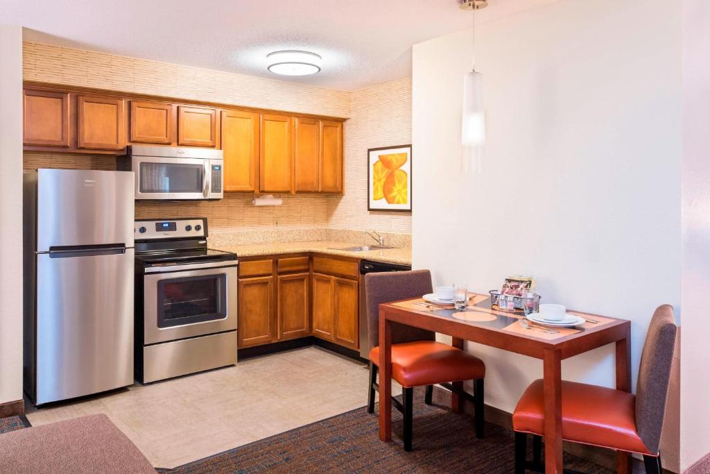 a kitchen with wooden cabinets and a table with chairs at Residence Inn Huntsville in Huntsville