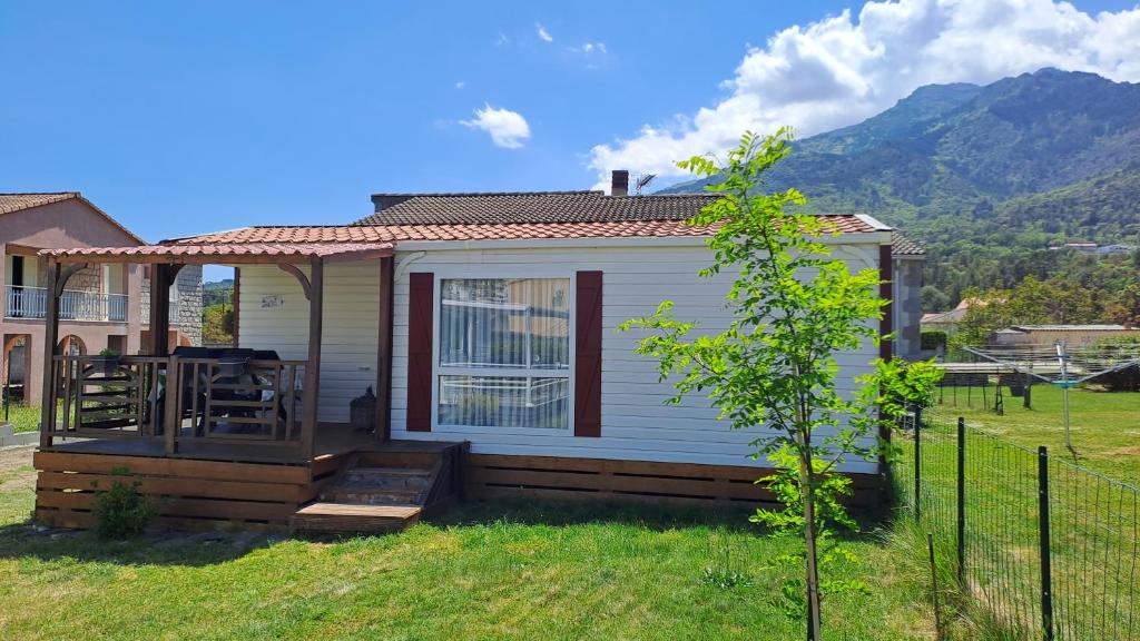 ein kleines weißes Haus mit einer Terrasse mit einem Tisch in der Unterkunft Muntagn' home in Corte
