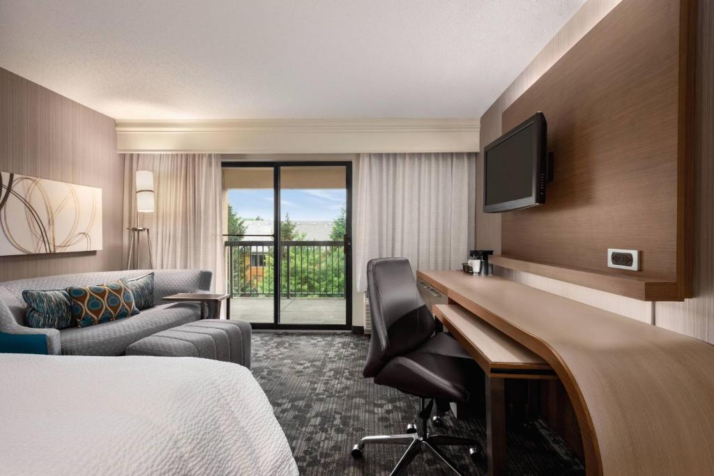 Habitación de hotel con cama, escritorio y TV. en Courtyard by Marriott Dayton North, en Dayton