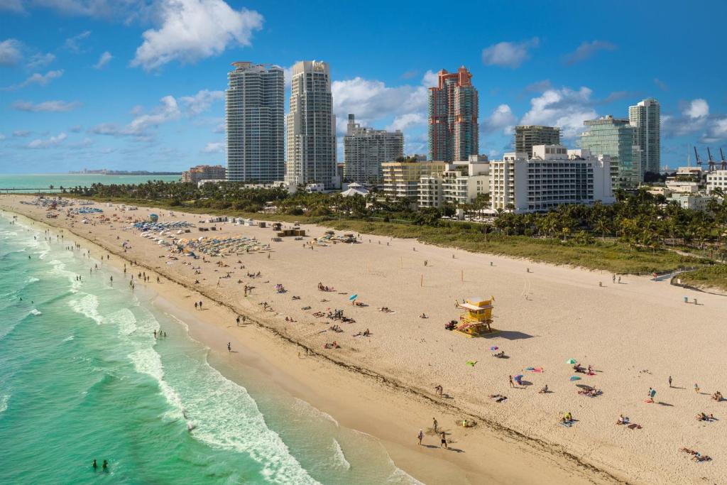a beach with people and the ocean and buildings at Marriott Stanton South Beach in Miami Beach