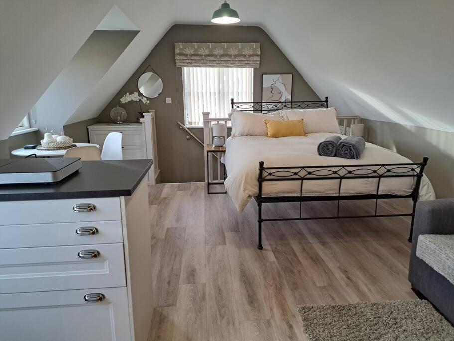 een slaapkamer met een bed en een bureau op zolder bij Suffolk View Apartment in Tuddenham