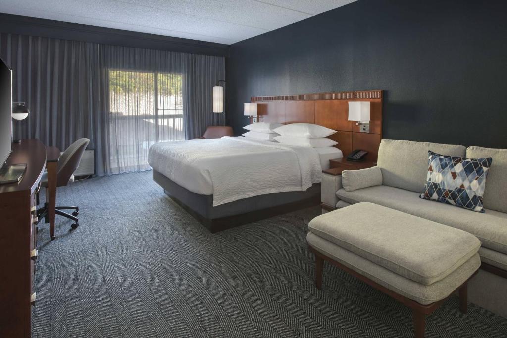 a large hotel room with a bed and a couch at Courtyard by Marriott Norwalk in Norwalk