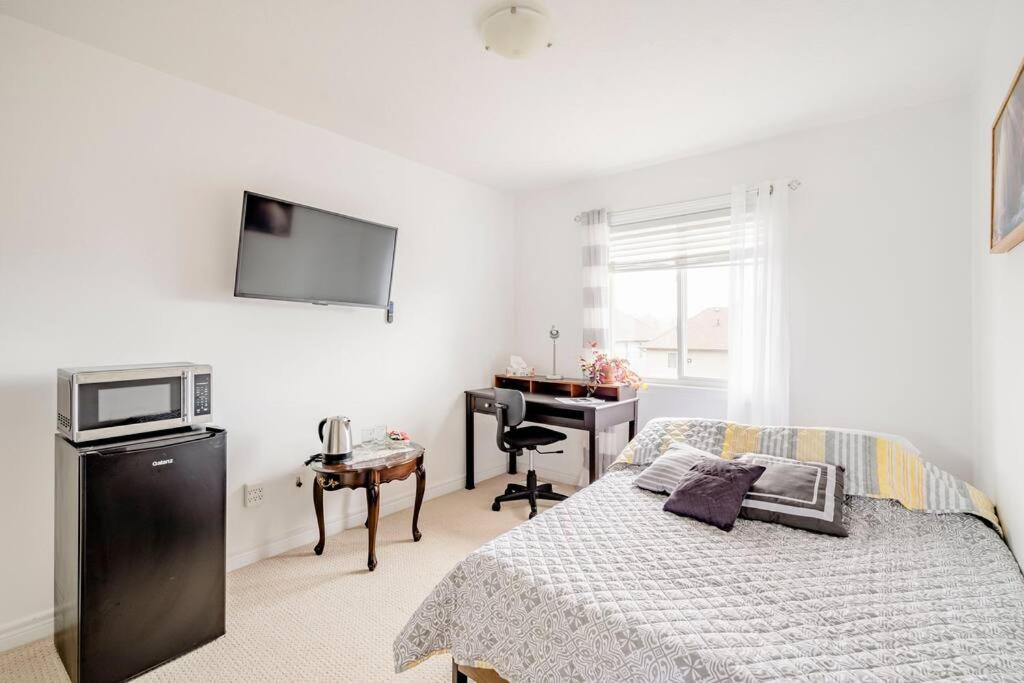 a bedroom with a bed and a desk and a television at Nimo Homestay in Guelph