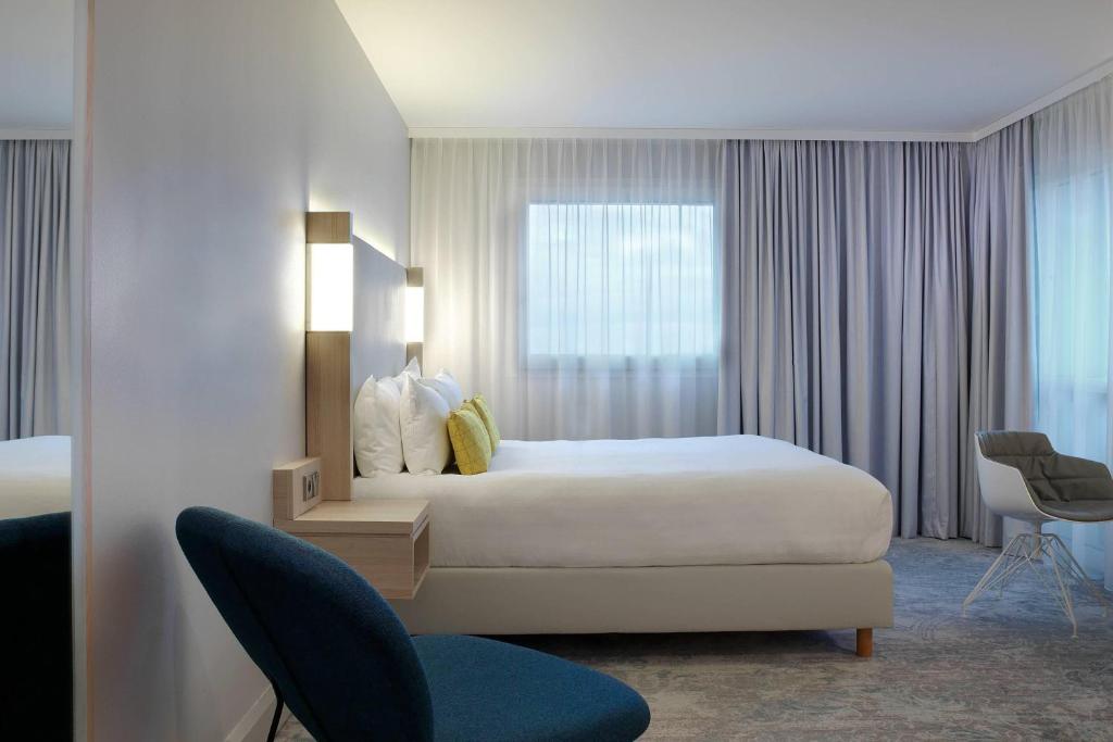 una camera d'albergo con letto e finestra di The Jangle Hotel - Paris - Charles de Gaulle - Airport a Le Mesnil-Amelot