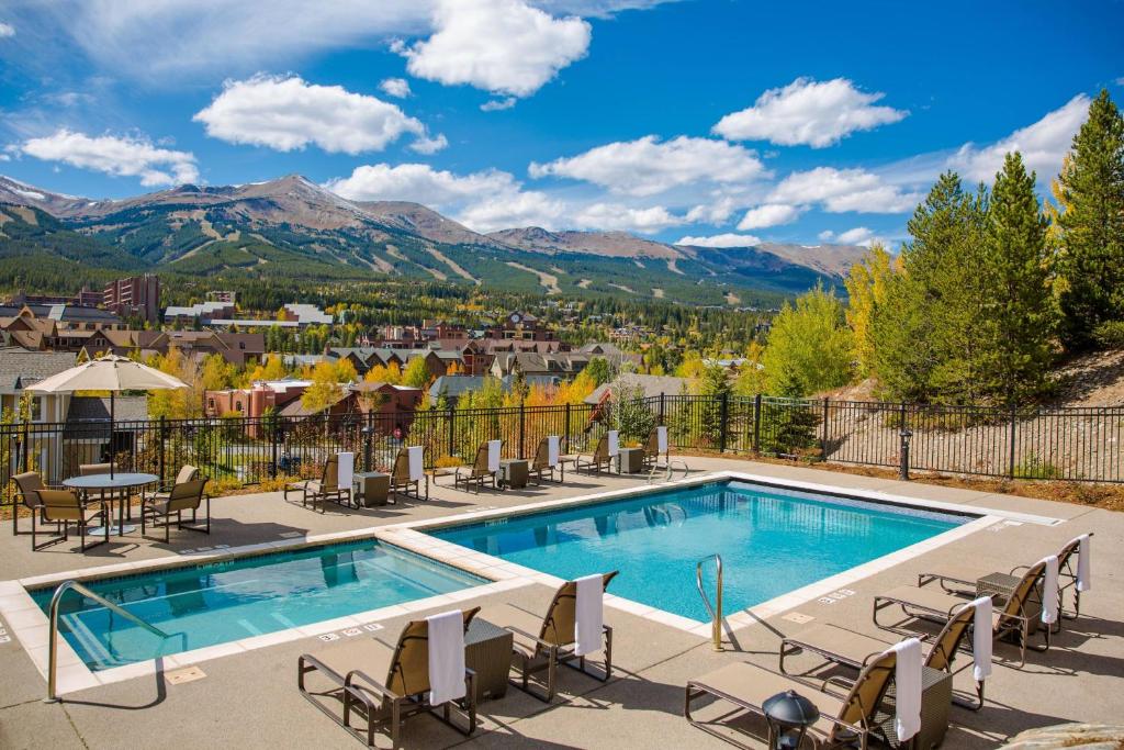 a pool with chairs and tables and mountains in the background at Residence Inn by Marriott Breckenridge in Breckenridge