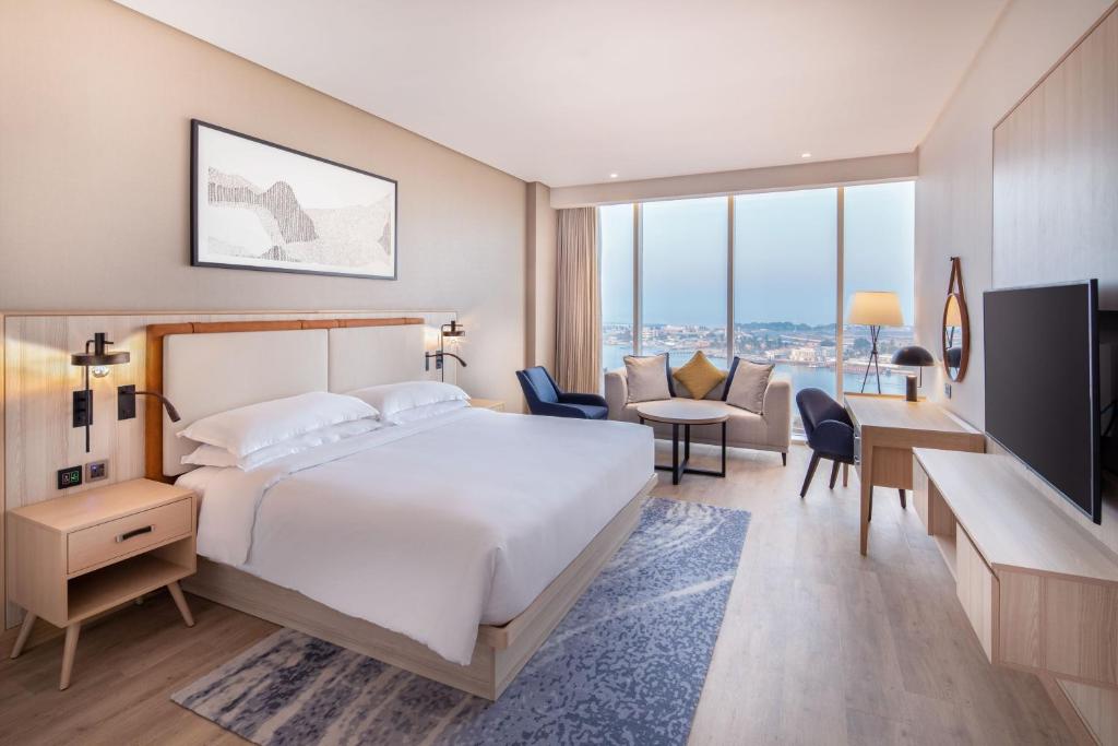 um quarto de hotel com uma cama, uma secretária e cadeiras em Four Points by Sheraton Jeddah Corniche em Jeddah