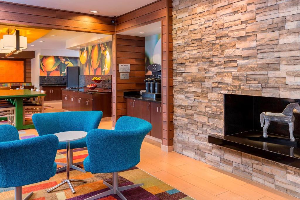 a lobby with a stone fireplace and blue chairs at Fairfield Inn & Suites Lubbock in Lubbock