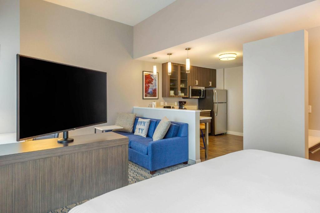 Residence Inn Providence Downtown في بروفيدينس: غرفة معيشة مع تلفزيون كبير وأريكة زرقاء