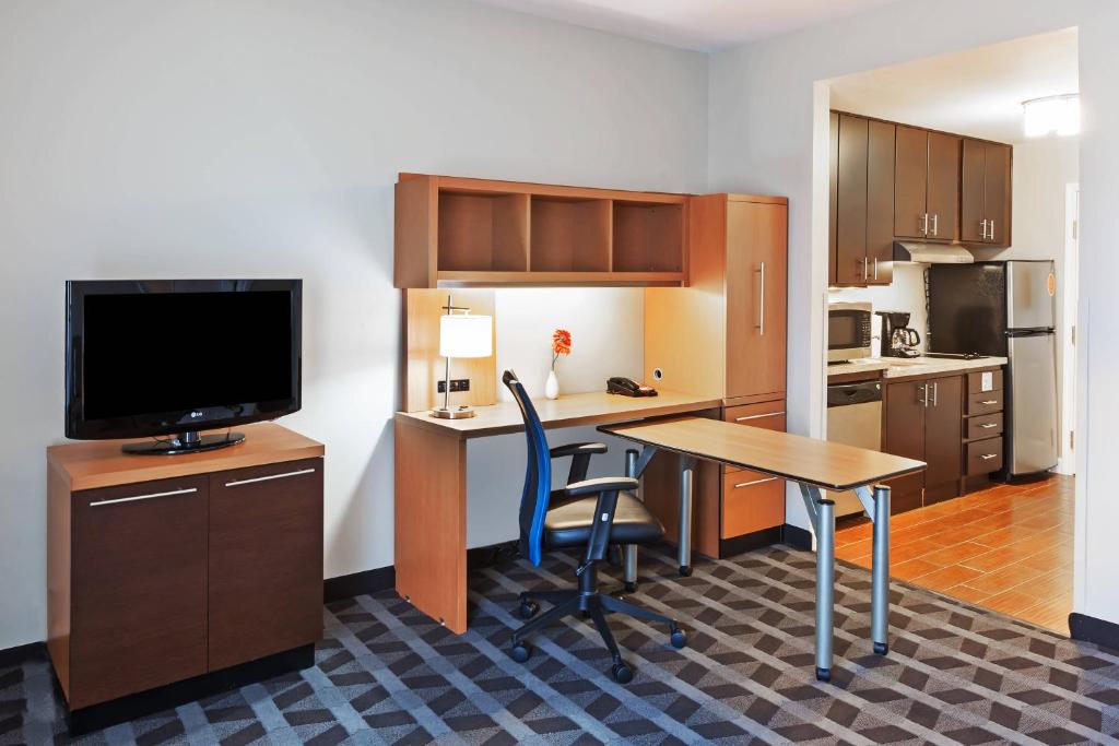 a kitchen with a desk with a television and a table at TownePlace Suites by Marriott Tulsa North/Owasso in Owasso