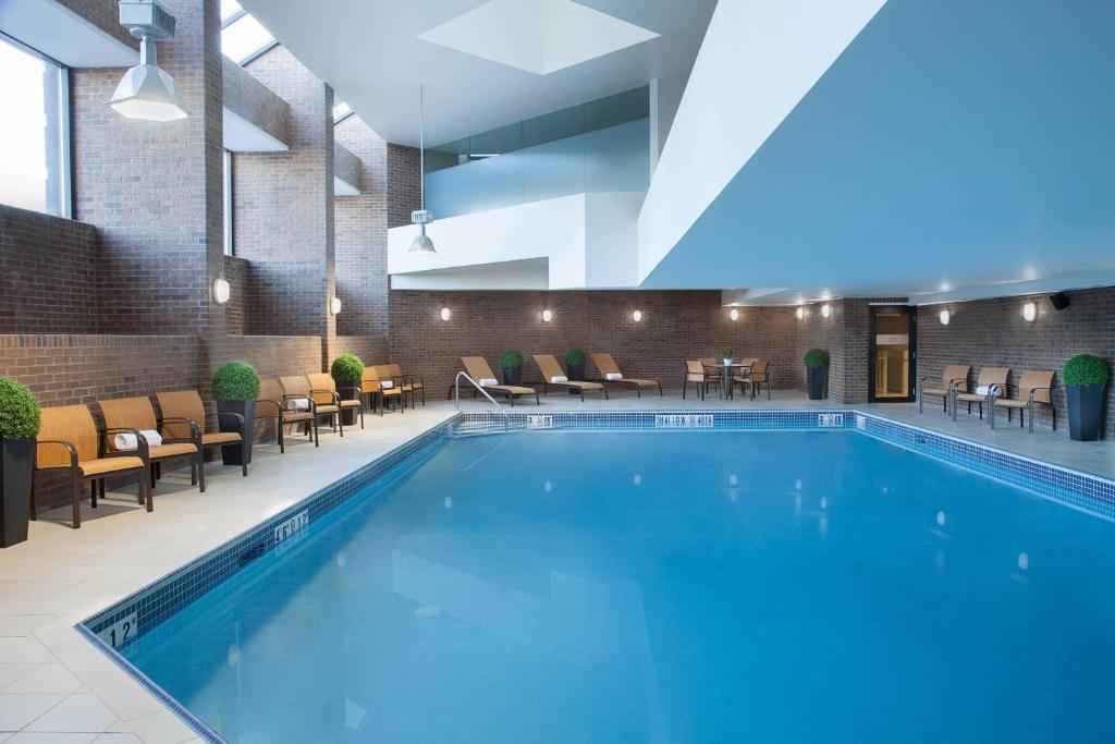 una piscina en un hotel con sillas y mesas en TownePlace Suites by Marriott Toronto Northeast/Markham, en Markham