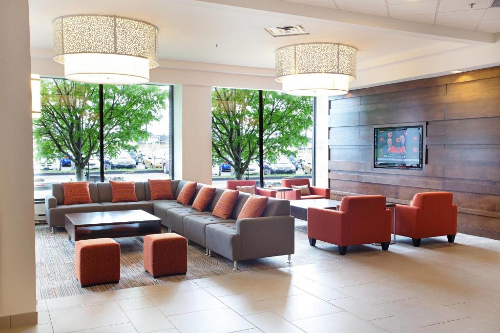 a lobby with a couch and chairs and windows at Delta Hotels by Marriott Saguenay Conference Centre in Saguenay