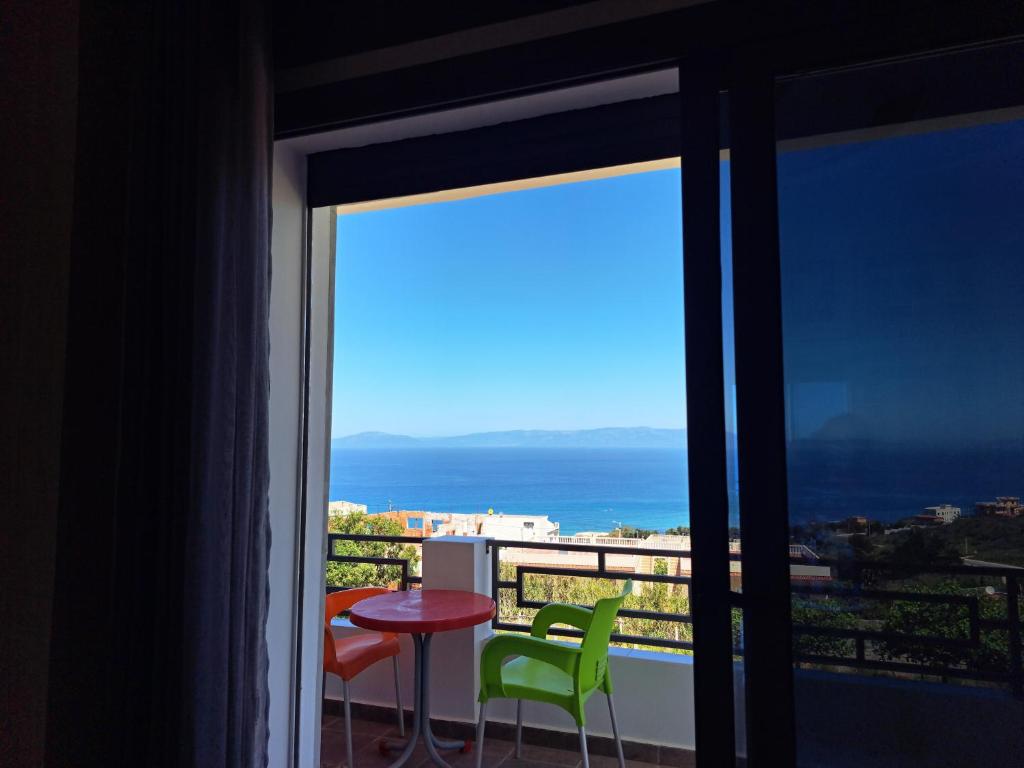 a balcony with a table and chairs and a view of the ocean at Blue Horizon-Ghougine in Tangier