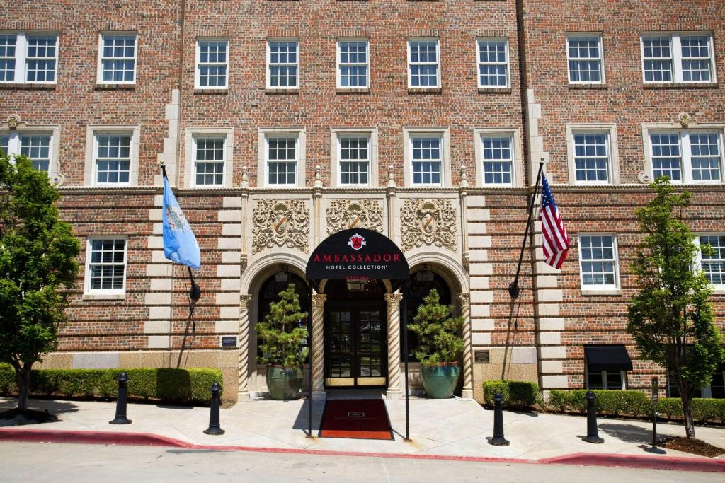 um grande edifício de tijolos com uma porta e duas bandeiras em Ambassador Hotel Tulsa, Autograph Collection em Tulsa