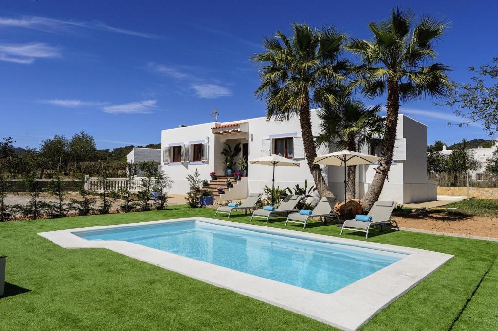 een villa met een zwembad en palmbomen bij Can Prats Country House in San Jose de sa Talaia