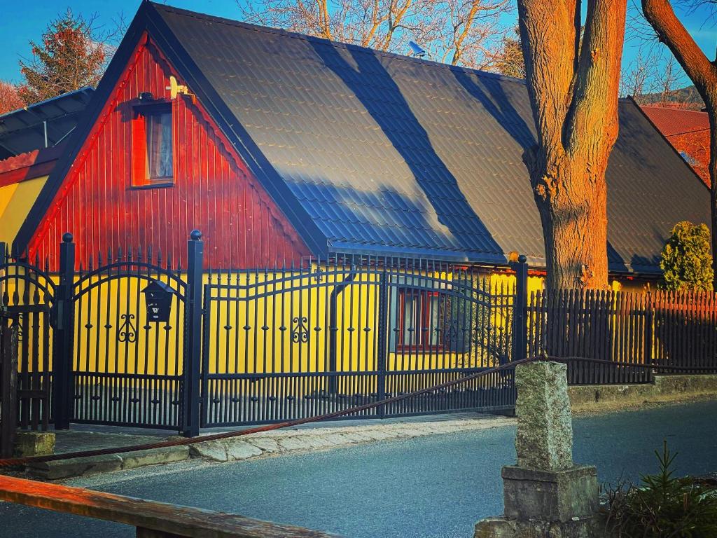 a red and yellow barn with a black fence at Chatka Baby Jagi in Ściegny